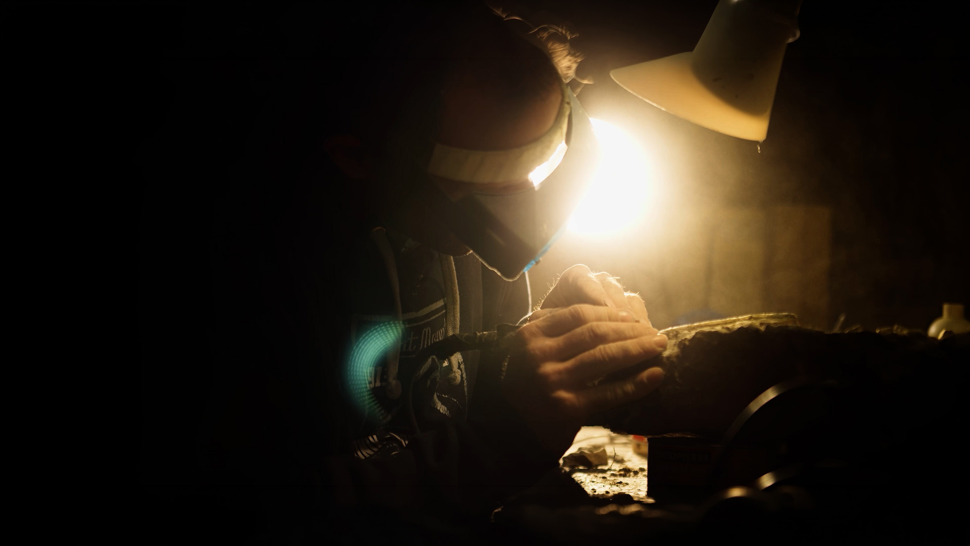 Préparation minutieuse d'un fossile sous la lampe, en atelier — film Empreinte